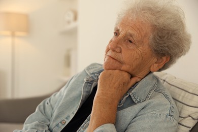 Photo of Loneliness concept. Sad senior woman sitting on sofa at home