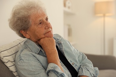 Photo of Loneliness concept. Sad senior woman sitting on sofa at home