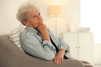 Photo of Loneliness concept. Sad senior woman sitting on sofa at home