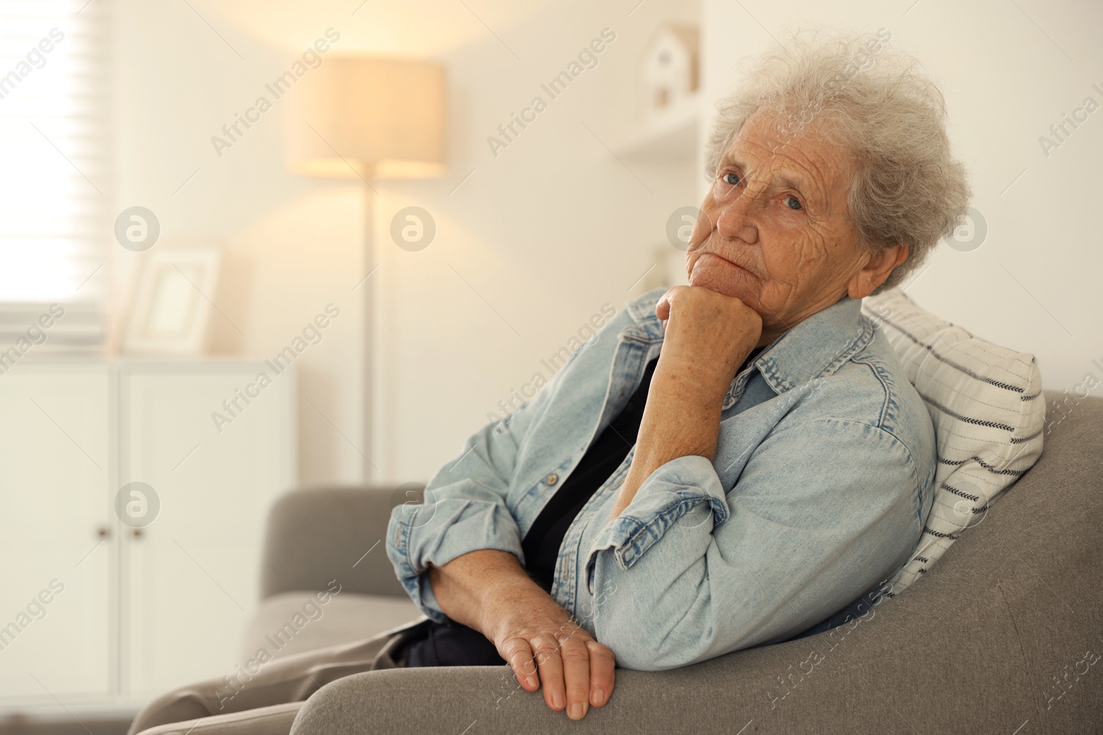 Photo of Loneliness concept. Sad senior woman sitting on sofa at home