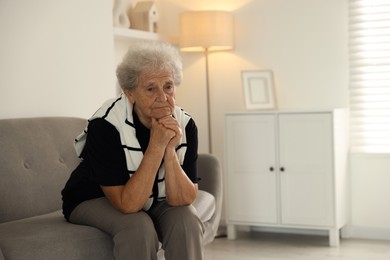 Photo of Loneliness concept. Sad senior woman sitting on sofa at home