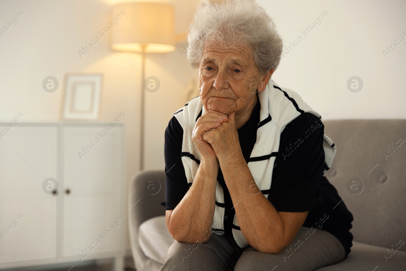 Photo of Loneliness concept. Sad senior woman sitting on sofa at home