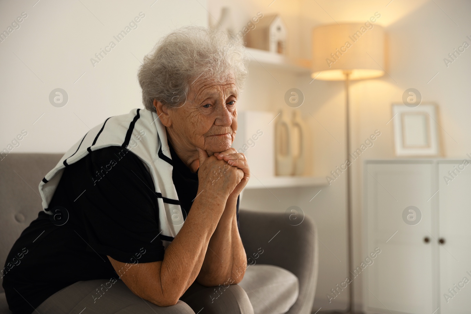 Photo of Loneliness concept. Sad senior woman sitting on sofa at home