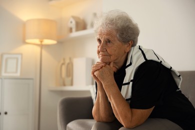 Loneliness concept. Sad senior woman sitting on sofa at home