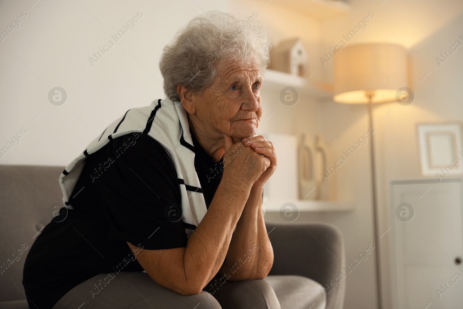 Photo of Loneliness concept. Sad senior woman sitting on sofa at home