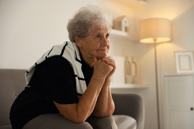 Photo of Loneliness concept. Sad senior woman sitting on sofa at home