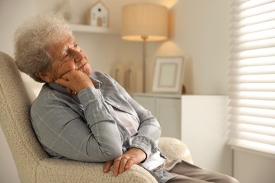 Photo of Loneliness concept. Sad senior woman sitting in armchair at home