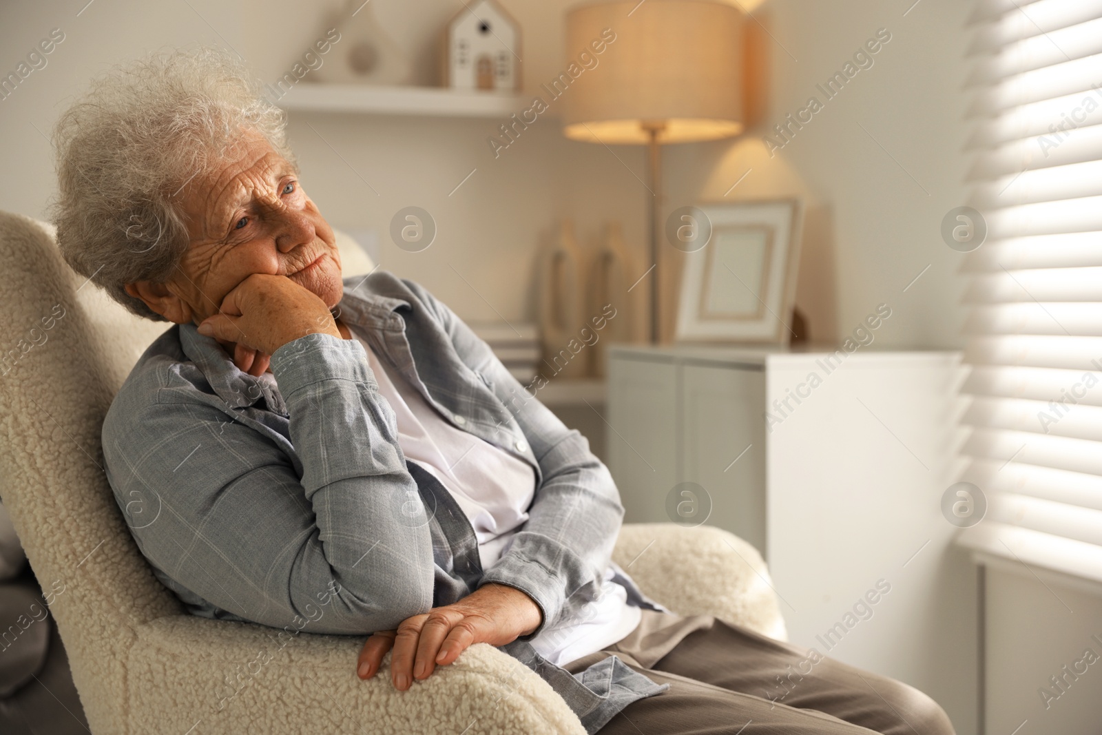 Photo of Loneliness concept. Sad senior woman sitting in armchair at home