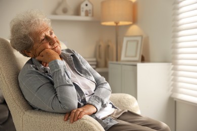 Photo of Loneliness concept. Sad senior woman sitting in armchair at home