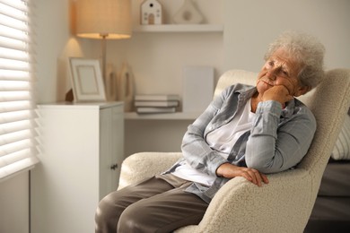 Photo of Loneliness concept. Sad senior woman sitting in armchair at home