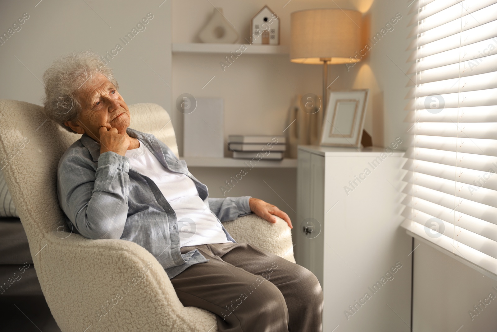 Photo of Loneliness concept. Sad senior woman sitting in armchair at home