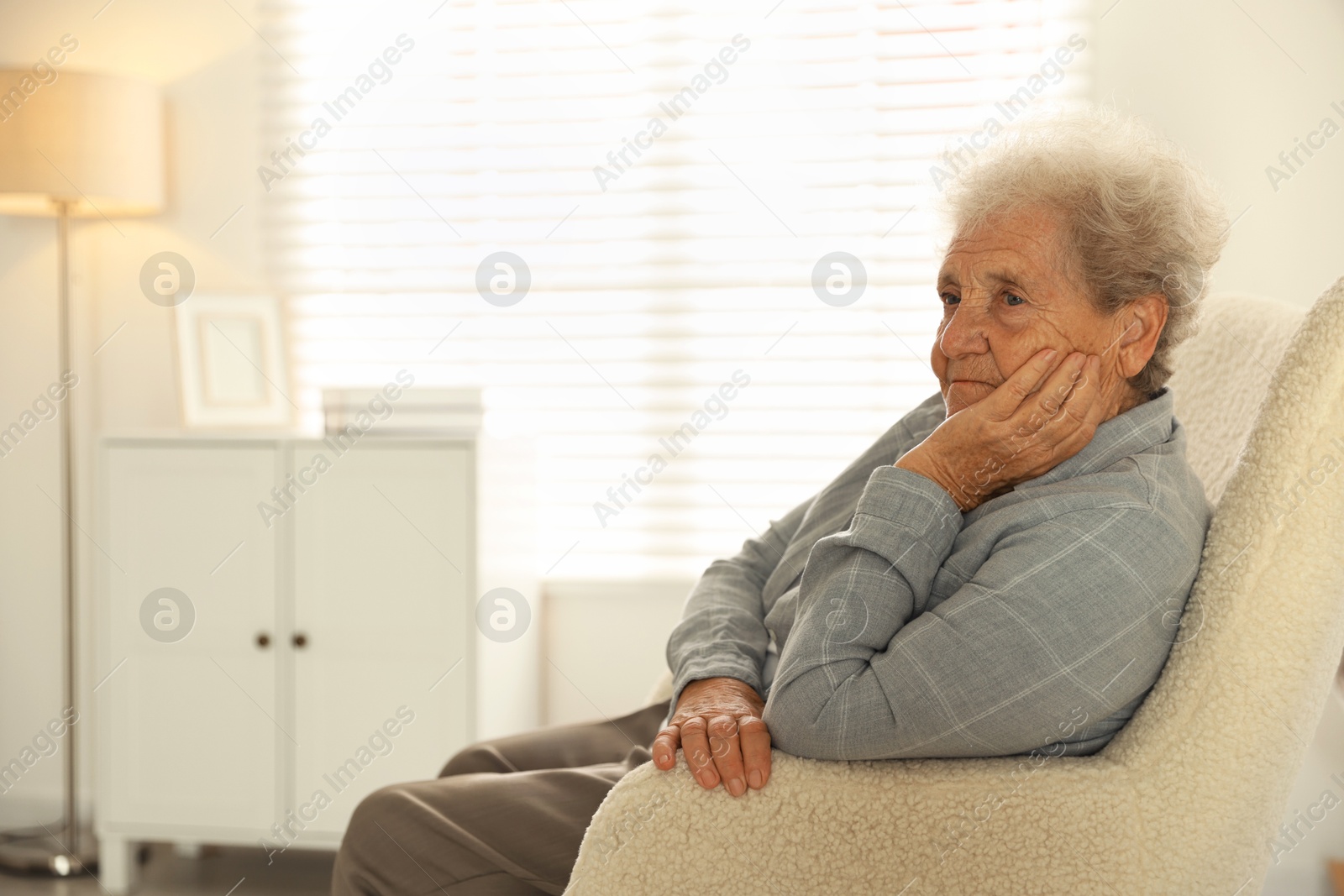 Photo of Loneliness concept. Sad senior woman sitting in armchair at home