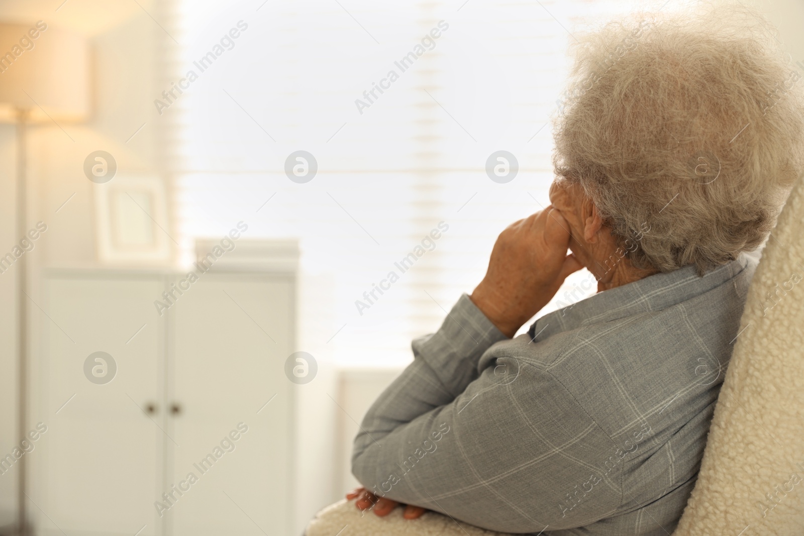 Photo of Loneliness concept. Sad senior woman sitting in armchair at home