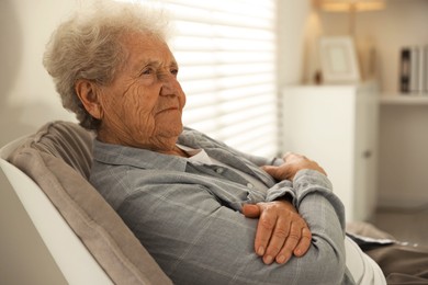 Photo of Loneliness concept. Sad senior woman sitting in armchair at home