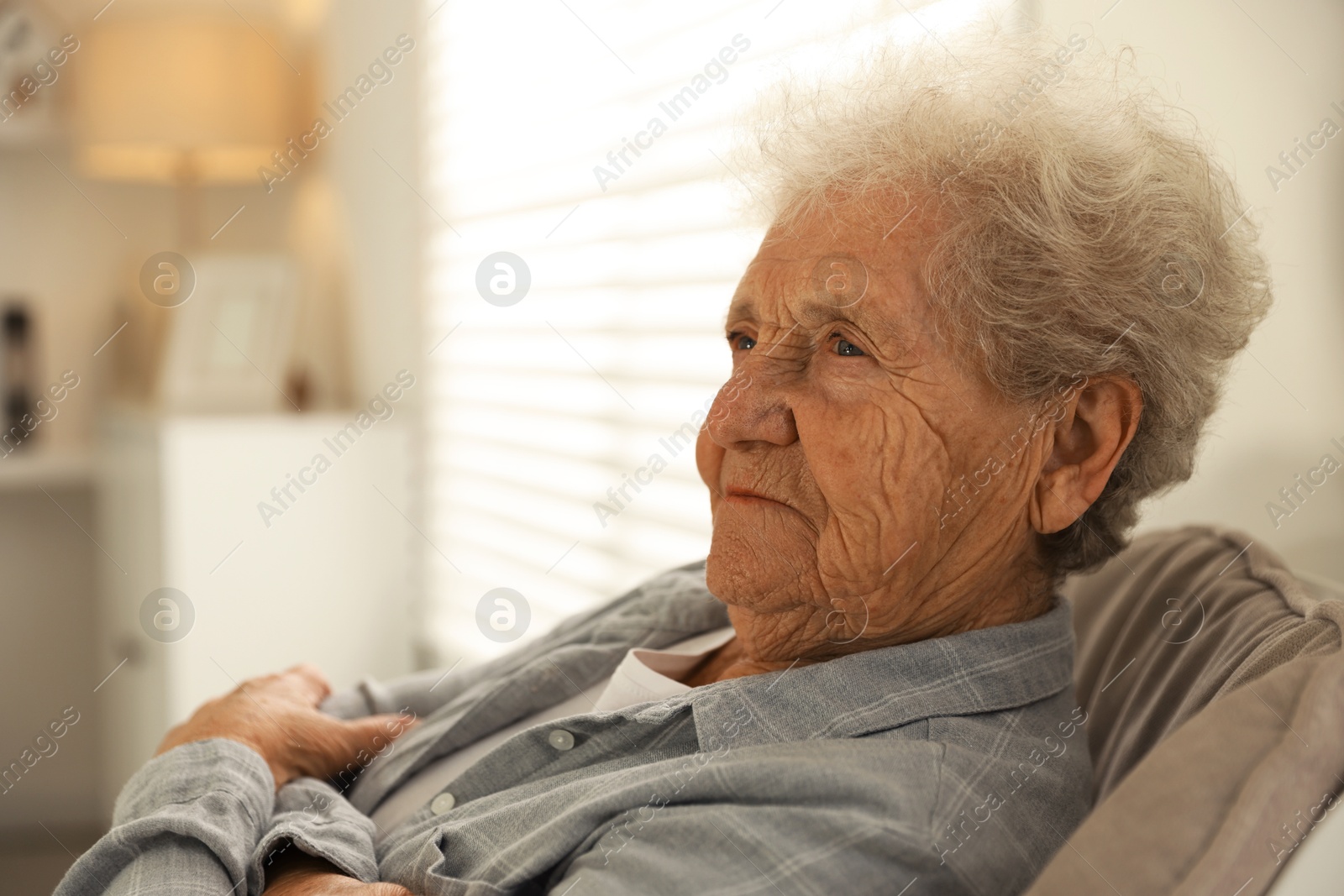 Photo of Loneliness concept. Sad senior woman sitting in armchair at home