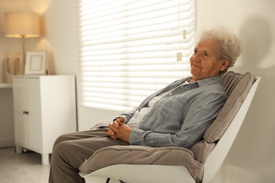 Photo of Loneliness concept. Sad senior woman sitting in armchair at home