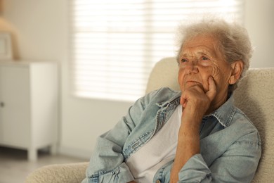 Photo of Loneliness concept. Sad senior woman sitting in armchair at home