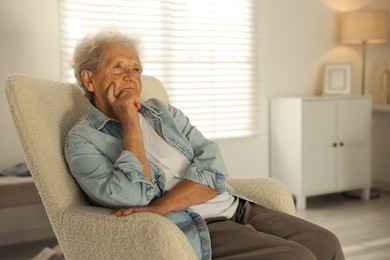 Photo of Loneliness concept. Sad senior woman sitting in armchair at home