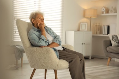 Photo of Loneliness concept. Sad senior woman sitting in armchair at home