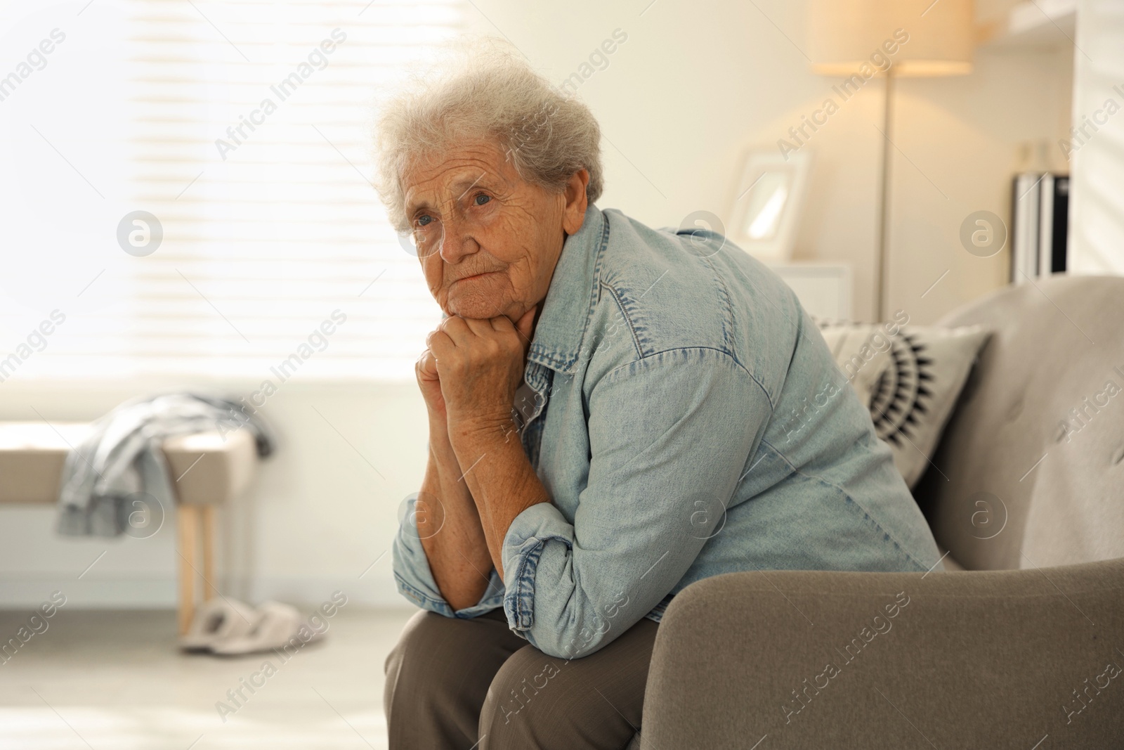 Photo of Loneliness concept. Sad senior woman sitting on sofa at home