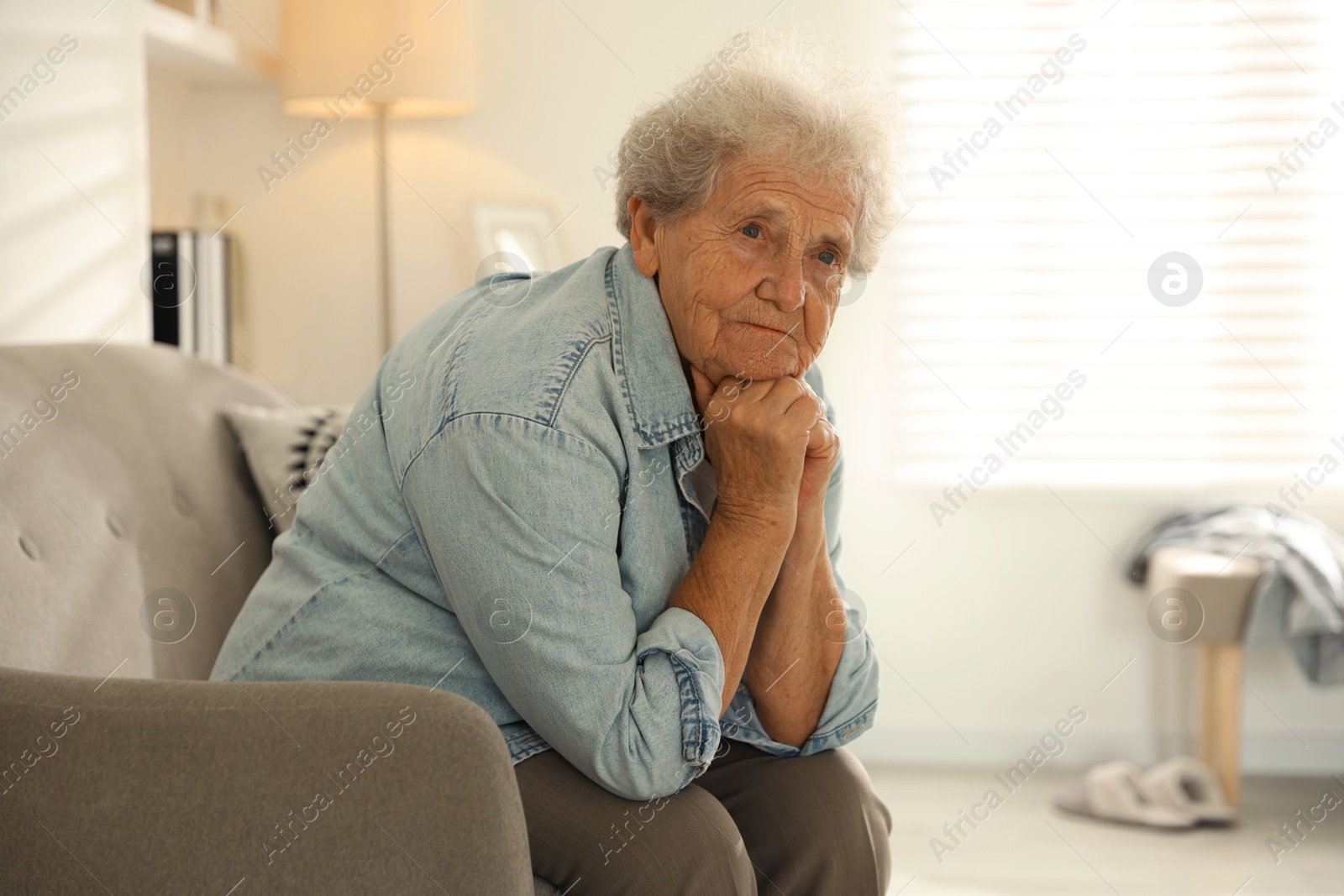 Photo of Loneliness concept. Sad senior woman sitting on sofa at home