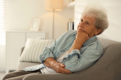 Photo of Loneliness concept. Sad senior woman sitting on sofa at home