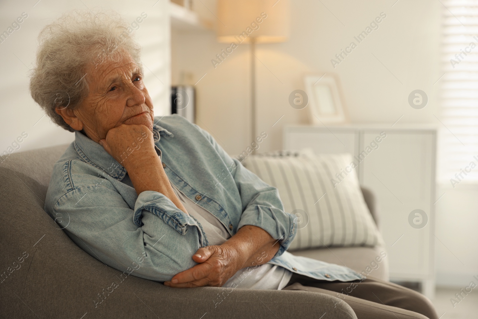 Photo of Loneliness concept. Sad senior woman sitting on sofa at home