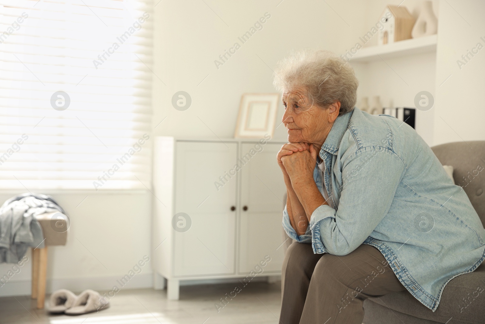 Photo of Loneliness concept. Sad senior woman sitting on sofa at home