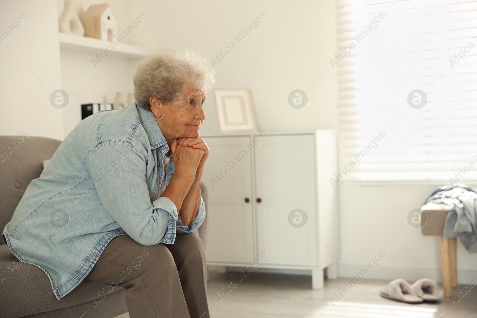 Photo of Loneliness concept. Sad senior woman sitting on sofa at home