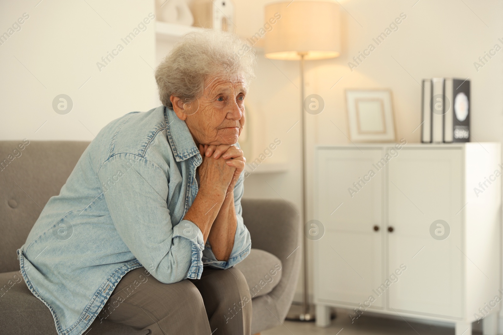 Photo of Loneliness concept. Sad senior woman sitting on sofa at home