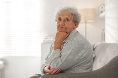 Photo of Loneliness concept. Sad senior woman sitting on sofa at home