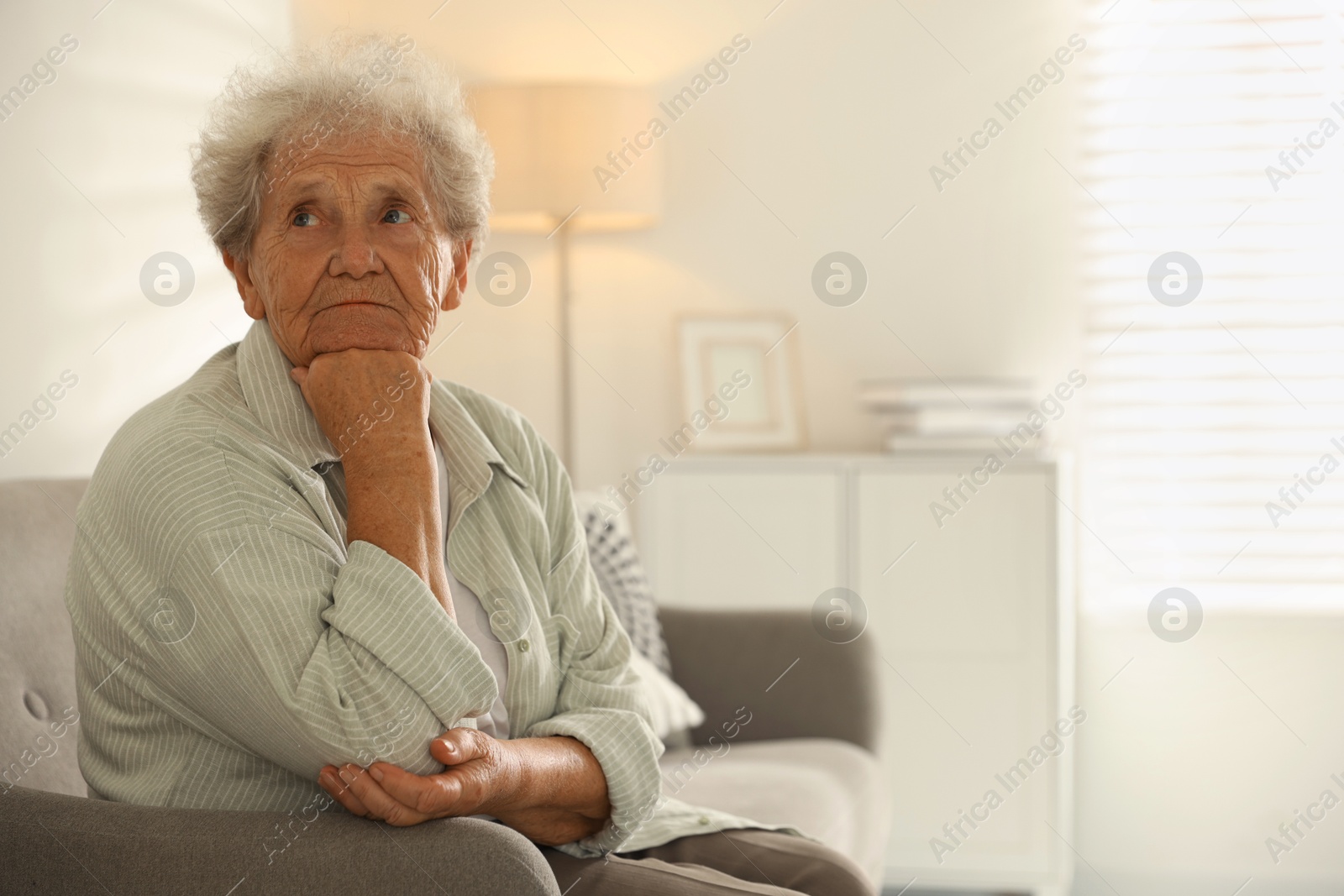 Photo of Loneliness concept. Sad senior woman sitting on sofa at home