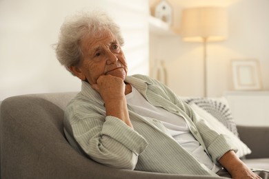 Photo of Loneliness concept. Sad senior woman sitting on sofa at home