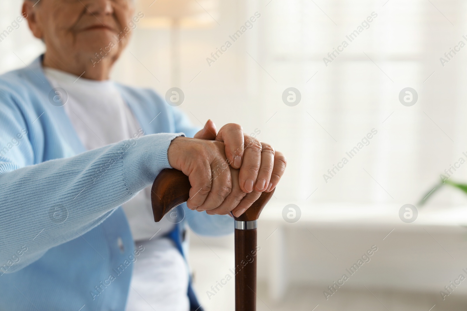 Photo of Lonely senior woman with walking cane indoors, closeup. Space for text