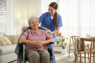 Photo of Caregiver covering senior woman with blanket indoors. Home health care service