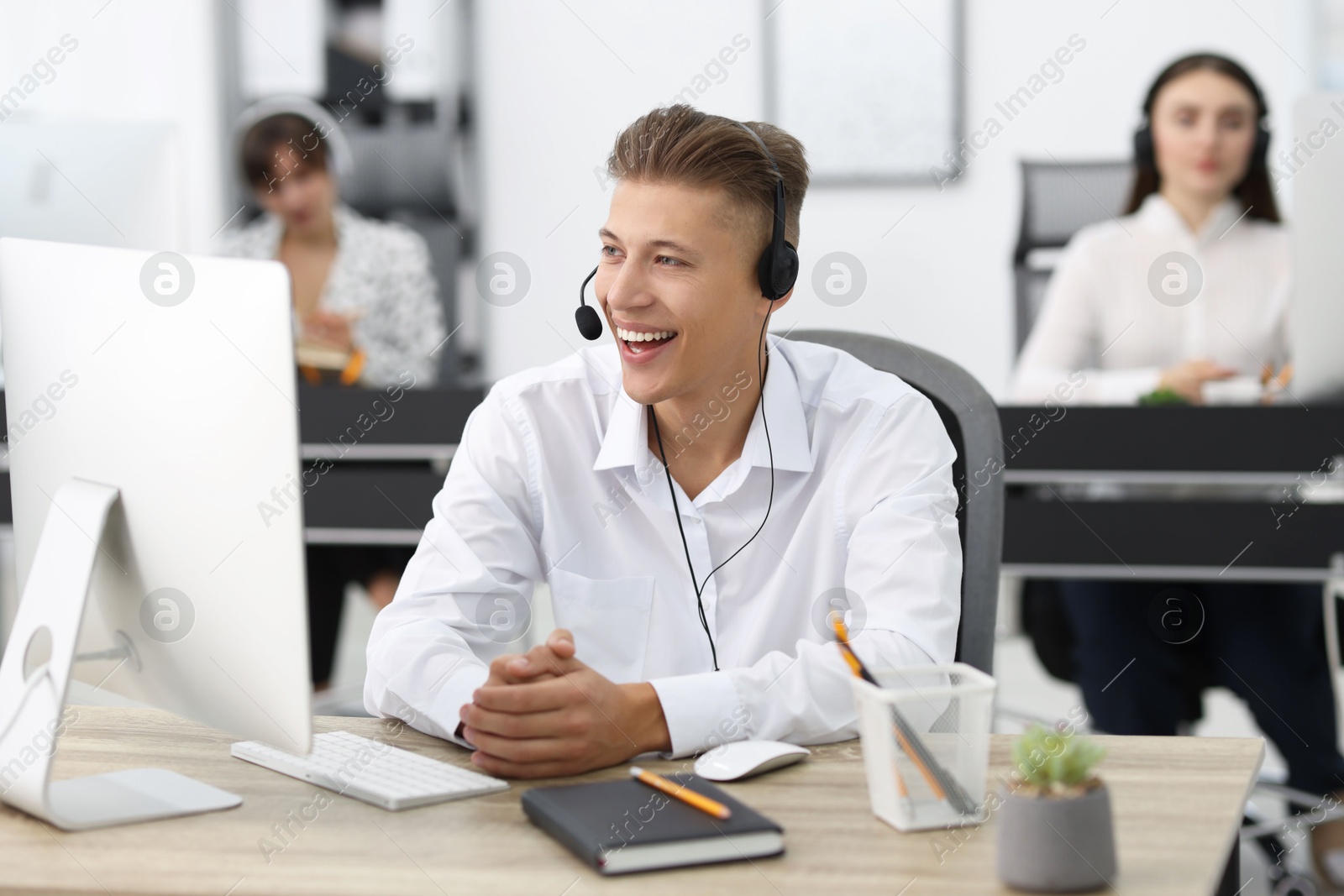 Photo of Salesman talking to client via headset at desk in office