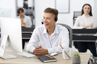 Photo of Salesman talking to client via headset at desk in office