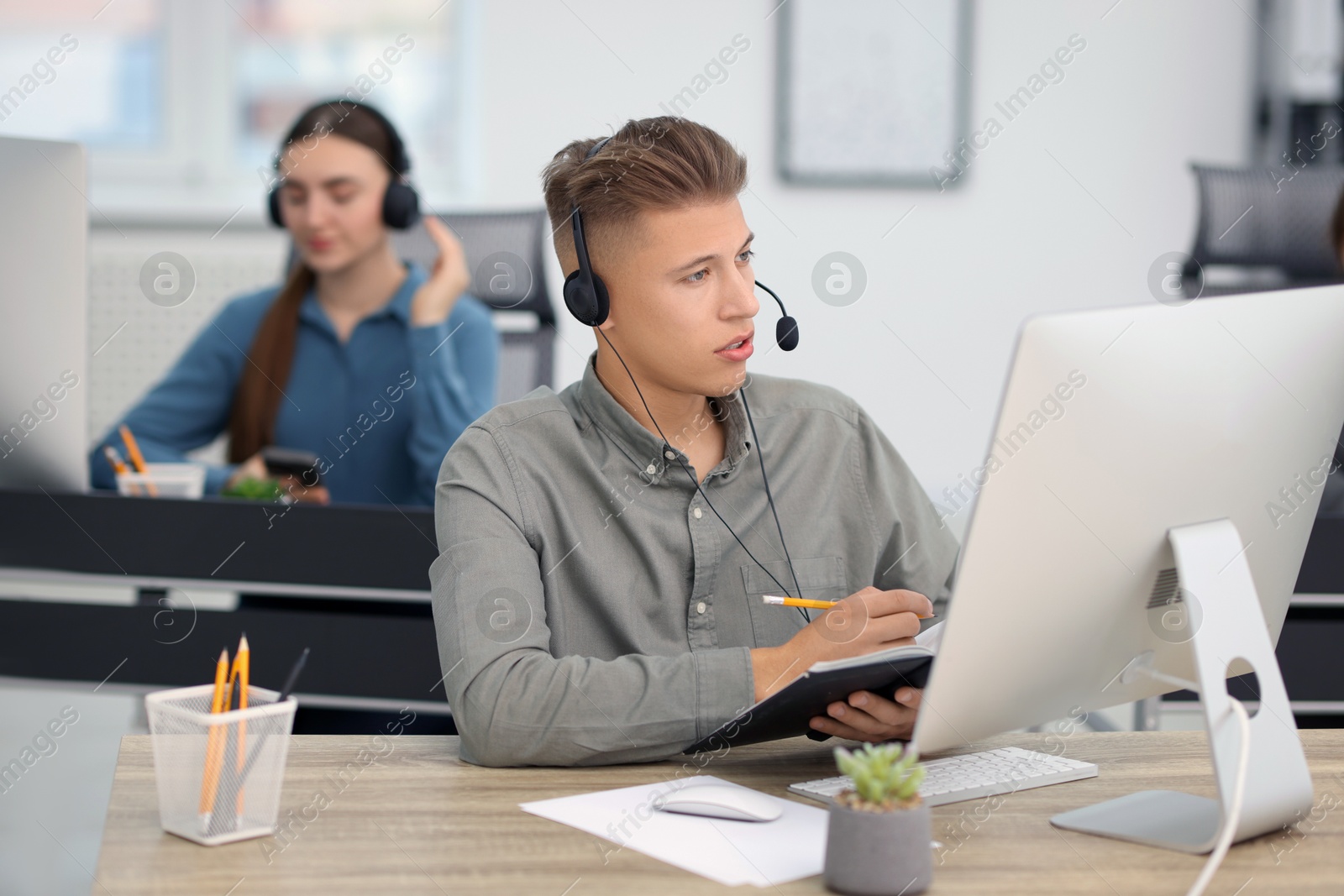 Photo of Salesman talking to client via headset at desk in office