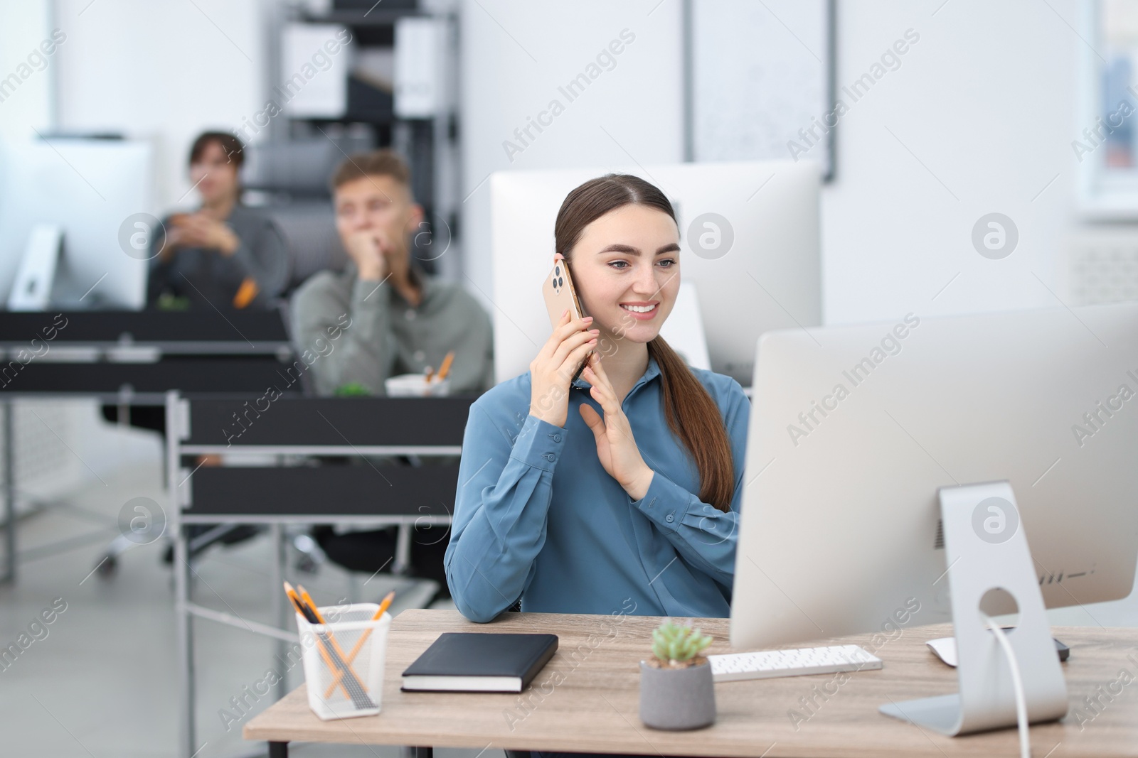 Photo of Saleswoman talking on phone at desk in office