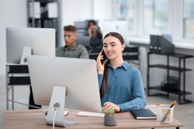 Photo of Saleswoman talking on phone at desk in office