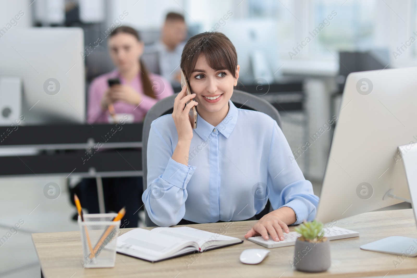 Photo of Saleswoman talking on phone at desk in office