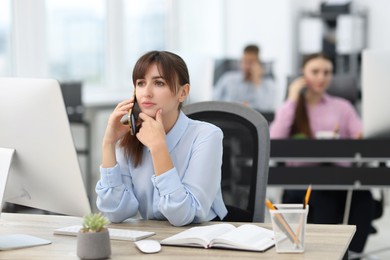 Photo of Saleswoman talking on phone at desk in office