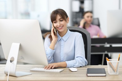 Photo of Saleswoman talking on phone at desk in office