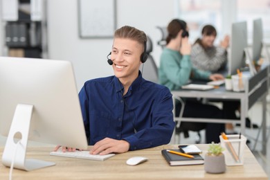 Photo of Salesman talking to client via headset at desk in office