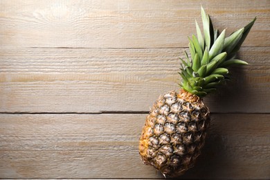 Photo of Fresh ripe pineapple on wooden table, top view. Space for text