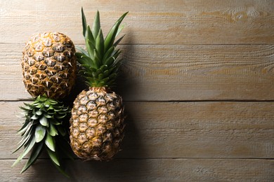 Fresh ripe pineapples on wooden table, flat lay. Space for text