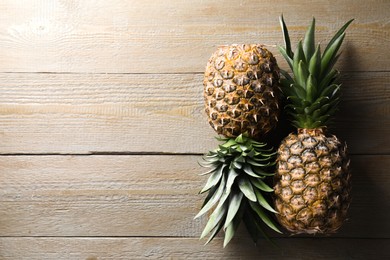 Photo of Fresh ripe pineapples on wooden table, flat lay. Space for text