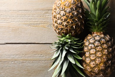 Fresh ripe pineapples on wooden table, flat lay. Space for text