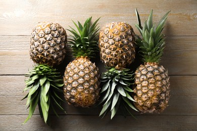 Photo of Fresh ripe pineapples on wooden table, flat lay