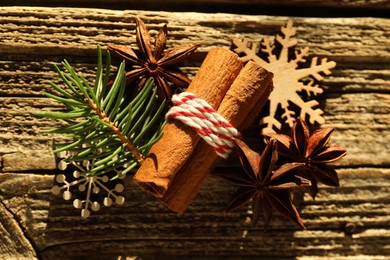 Photo of Aromatic anise stars and cinnamon sticks with Christmas decor on wooden table, flat lay